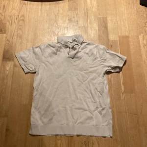 Beige pikétröja från H&M - Säljer en stilren beige pikétröja från H&M. Tröjan har korta ärmar och en klassisk krage. Perfekt för en avslappnad och snygg look.