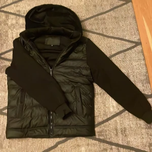 Jacka/Cardigan - Snygg svart cardigan som håller värmen till 100%.Den är knappt använd. Säljer den för att den är förstor. Jackans inner sida är gjord på 100% polyester. Skriv till mig för mer info.