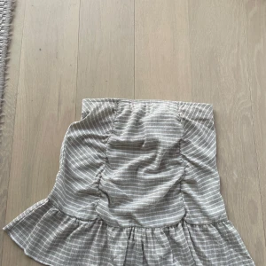 Kjol med volang  - Säljer en söt randig kjol i beige och vit med volangdetalj. Kjolen är ganska kort och den är aldrig använd! 