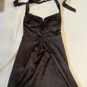 Svart y2k halterneckklänning - Säljer denna fina y2k halterneckklänningen. Kort i längd, ungefär till låren, fin med knytning i ryggen eller nacken. Storlek L men passar som en S/M