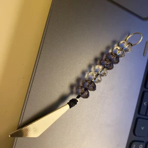 Nyckelring med pärlor och metallhänge - Snygg nyckelring med transparenta och lila pärlor samt ett triangulärt metallhänge. Perfekt accessoar för att ge dina nycklar en personlig touch. Handgjord nyckelring eller telefon asccessoar.