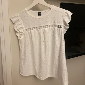 Vit blus med spetsdetaljer - Säljer en söt vit blus från med spetsdetaljer och volangärmar. Blusen har en luftig passform och är perfekt för varmare dagar samt väldigt stretchig. Perfekt för sommaren och aldrig använt.