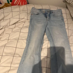 Ljusblå jeansbyxor från LAB - Snygga ljusblå jeansbyxor från LAB med klassisk femficksdesign. Byxorna har en bootcut-stil och är perfekta för en avslappnad look. De är tillverkade i ett bekvämt denimtyg som ger en skön passform.