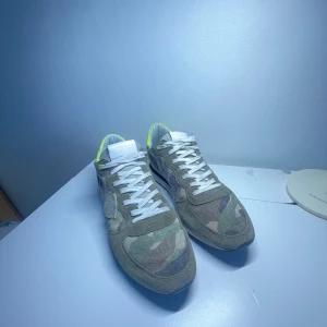 Phillipe model runners storlek 43 - Snygga sneakers i camouflage-mönster med neongula detaljer. Skorna har vita snören och en robust sula. Väldigt bra skick ungefär 8/10 dock ingen box därför priset är så bra. Har du frågor e de ba o skicka ett meddelande 