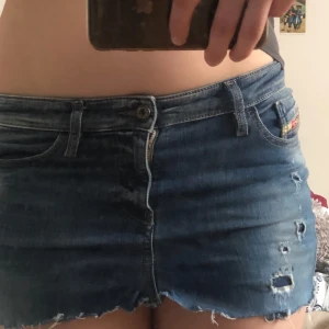 Blå jeansshorts från Diesel - Snygga blå jeansshorts från Diesel med slitna detaljer och fransar. De har en klassisk femficksdesign och knappgylf. Perfekta för en avslappnad stil. Klippte själv så inte helt jämt men tyckte det var lite coolt