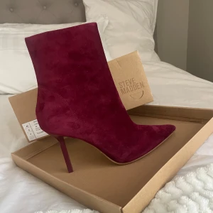 Vinröda stövletter från Steve Madden - Snygga vinröda stövletter i mocka från Steve Madden med spetsig tå och klack. Perfekta för att ge en elegant touch till din outfit. Helt oanvända! Nypris 1699kr