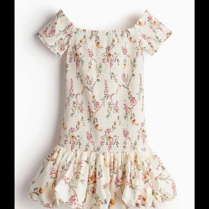 Blommig offshoulder klänning - Charmig offshoulder klänning med blommigt mönster. Klänningen har korta ärmar och en volangdetalj vid fållen. Perfekt för somriga dagar🌸