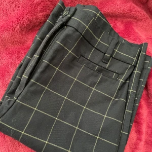 Blåa rutiga kostymbyxor  - Snygga blåa kostymbyxor med ett stilrent rutmönster i vitt. Utsvängda ner till benen. Har två dubbletter , så har ingen användning för de. Storlek 34