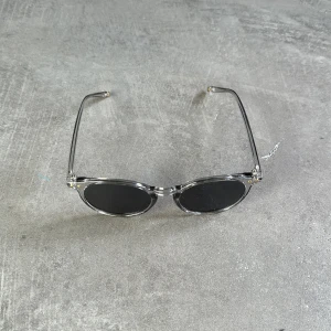 Runda solglasögon med transparent båge - Snygga runda solglasögon med transparent båge och mörka linser. Perfekta för en stilren look. De har en klassisk design som passar de flesta ansikten.