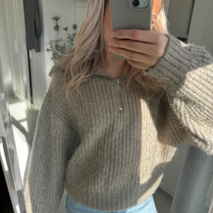 Beige stickad tröja från Gina Tricot - Säljer en mysig beige stickad tröja från Gina Tricot med dragkedja framtill. Perfekt för kyliga dagar med sin ribbade design och långa ärmar. En stilren och bekväm tröja som passar till det mesta. 🌟