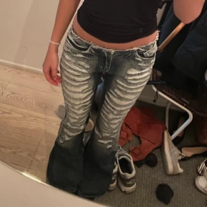 London jaded jeans - Snygga blå bootcut jeans med en unik tvättad look. De har en lågmidjad passform och är perfekta för en avslappnad stil. Jeansen har klassiska fem fickor och en dragkedja framtill.