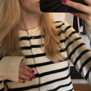 Randig kofta från H&M - Säljer en stilren randig kofta från H&M i svart och vit. Koftan har långa ärmar och knappar framtill. Perfekt för alla årstider🥰 fortfarande prislapp kvar!