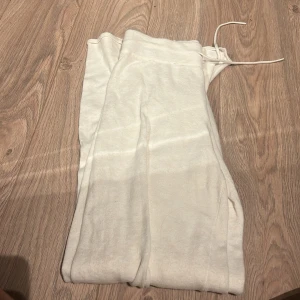 Vita mjukisbyxor med snörning - Säljer ett par vita mjukisbyxor med snörning i midjan. Perfekta för en avslappnad stil och bekväma att bära. Byxorna har en enkel design och är gjorda i ett mjukt material.