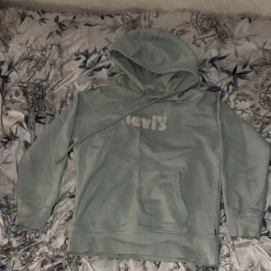 Ljusblå hoodie från Levi's - Säljer en ljusblå hoodie från Levi's med klassisk logga på bröstet. Tröjan har en stor ficka framtill och justerbar huva med dragsko. Andvänds några gånger men funkar bra iallafall