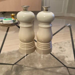 Beige salt- och pepparkvarn från Le Creuset - Säljer ett set med beige salt- och pepparkvarn från Le Creuset. Kvarnarna har en elegant design med bokstäverna 'S' och 'P' på toppen för enkel identifiering. Perfekt för att ge köket en stilren touch. Aldrig använda 