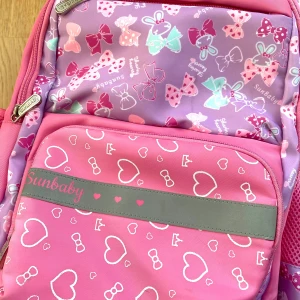 Rosa kawaii ryggsäck  - Söt rosa ryggsäck från Sunbaby med hjärt- och rosettmönster. Den har flera fack med dragkedja och justerbara axelremmar. Perfekt för dotter eller lillasyster🎀i tåligt och tjockt material, har liten nästan osynlig fläck på framsidan, men som sagt inget man märker! Ryggsäcken är ca 43x39 cm💞