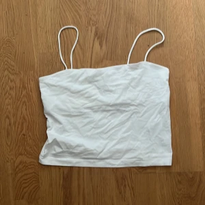 Vit linnetopp från Gina Tricot - Säljer en enkel och stilren vit linnetopp från Gina Tricot. Toppen har smala axelband och är perfekt för varma dagar. Den är gjord i ett mjukt och bekvämt material.