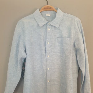 Ljusblå skjorta i linne. - Säljer en stilren ljusblå skjorta från Lindex. Skjortan har en klassisk krage och knappar framtill. Perfekt för en avslappnad men ändå uppklädd look.