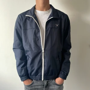 Vårjacka Gant - Riktigt snygg ofodrad Gantjacka perfekt nu till våren/sommaren. Storlek: 170 Skick: 8/10 en pytteliten slitning på högerarmen, syns på tredje bilden. Har ni några frågor är det bara att fråga på! Pris inte hugget i sten så kom gärna med förslag!