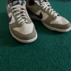 Nike Dunk i grått och vitt - Snygga Nike Dunk sneakers i en stilren kombination av grått och vitt. Skorna har klassisk snörning och en bekväm passform. Perfekta för en casual look. Mycket fint skick, skulle nog säga använda 1-3 gånger! Storleken är 43 men skulle nog säga passar 42☺️