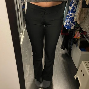 Lågmidjade kostymbyxor från BikBok - Snygga svarta lågmidjade kostymbyxor från BikBok i storlek 34. Byxorna har en klassisk design med en rak passform och slits nedtill, perfekta för en stilren look.😊    OBS! De har en liten fläck på benet