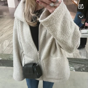 Beige teddyjacka med dragkedja - Mysig beige teddyjacka med dragkedja framtill och två stora fickor. Perfekt för kyliga dagar när du vill hålla dig varm och stilren. Jackan har en avslappnad passform och långa ärmar.Stolken är i L men jag bär den som har xs/s allså är den lite oversized för mig!🥰
