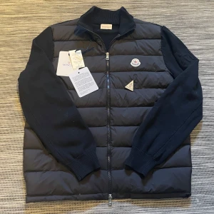 Svart dunväst från Moncler - Säljer min snygga cardigan från Moncler! Jag vill gärna behålla den men säljer den eftersom den var för stor. Den är i mycket bra skick! 9/10 skick. Den har ett snyggt M vid sidan om armen och den klassiska Moncler loggan där framme. NFC-scan fungerar (se bild) och om man går in på länken så kommer man till monclers hemsida. Allting som finns på bilderna tillkommer. Om ni har några andra frågor eller önskar fler bilder så är det bara att höra av er! Pris kan diskuteras vid snabb affär😉