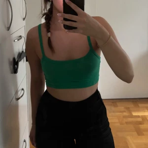 Grön croppad linnetopp - Snygg grön croppad linnetopp med smala axelband och enkel, stilren design. Toppens material känns mjukt och stretchigt, vilket gör den superbekväm att bära. Passar även en xs! 