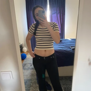 Randig croppad topp från Gina Tricot - Säljer en croppad topp från Gina Tricot i beige med svarta horisontella ränder. T-shirten har rund halsringning, korta ärmar och är stickad i ett mjukt material. Perfekt för dig som gillar en enkel men trendig look. Däremot har tröjan några små fläckar på backsippan av ena axeln men annars är den i topp skick💗