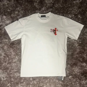 Chrome hearts T Shirt - Säljer: Chrome Hearts Multi Color Cross T-shirt – Vit – Strl XL Säljer en snygg och stilren Chrome Hearts T-shirt i vitt med flerfärgat cross-tryck både fram och bak. Modellen är oversized i passformen och passar perfekt för dig som gillar streetwear med lite edge. Nyskick  ✅ Storlek: XL ✅ Färg: Vit med flerfärgat tryck ✅ Skick: Ny / Endast testad ✅ Material: 100% bomull ✅ Chrome Hearts-tag nertill  Unik och iögonfallande design med högkvalitativt tryck. Passar nog L också