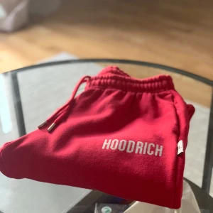 Röda mjukisbyxor från Hoodrich M - Riktigt snygga röda mjukisbyxor från Hoodrich i storlek M. Byxorna har elastisk midja med dragsko och Hoodrich-logga tryckt på benet. Mjukt material och klassisk passform, perfekta för chill eller streetwear. Snygga metalldetaljer på snörena.