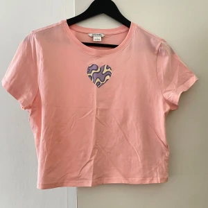 Rosa croppad topp med hjärta |L - Söt croppad rosa topp från Monki med ett unikt hjärta i lila, gult och svart på bröstet. Nyttskick men prislapp saknas. 