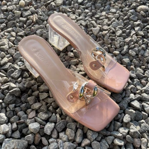 Beiga sandaler med transparent klack - Snygga sandaler i beige med transparenta remmar och chunky klack i plexiglas. Dekorerade med en stor guldfärgad kedjedetalj framtill och fyrkantig tå. Perfekta för dig som vill sticka ut med trendiga detaljer och modern design.