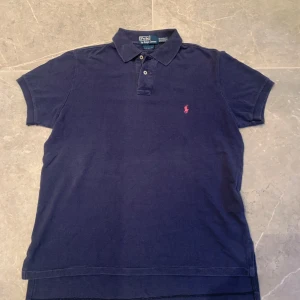 Mörkblå pikétröja Ralph Lauren storlek M - Mörkblå pikétröja från Ralph Lauren – Strl M – 150 kr  Klassisk piké från Polo Ralph Lauren i mörkblå färg med den ikoniska röda loggan broderad på bröstet. Stilren och tidlös modell med kort ärm och krage. Passar både till vardags och lite mer uppklädda tillfällen.  ✔ Storlek: M ✔ Färg: Mörkblå ✔ Märke: Polo Ralph Lauren ✔ Skick: Bra begagnat skick – inga hål eller fläckar, endast normalt slitage
