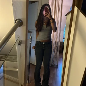 Svarta bootcut jeans Gina Tricot - Säljer ett par svarta bootcut jeans från Gina Tricot med låg midja. Jeansen har klassisk femficksdesign, dragkedja och dubbla knappar framtill. Snygg tvättad look och raka ben med lätt utsvängning nertill. Perfekta till sneakers eller boots.