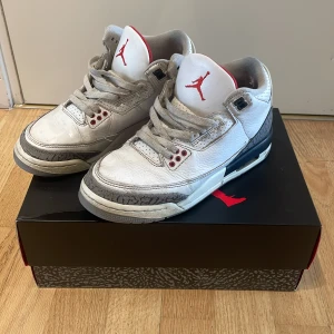 Nike Air Jordan 3 Retro OG Vit/Röd - Nike Air Jordan 3 Retro OG sneakers i vitt skinn med grå och svarta detaljer samt röda accenter. Klassisk elephant print runt tån och hälen, röd Jumpman-logga på plösen och robust sula med synlig Air-enhet. 