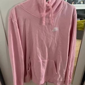 Rosa Nike Hoodie - Rosa hoodie från Nike, Tröjan har en vit Nike-logga på bröstet, huva med snörning och en stor magficka. Storlek M 🌻