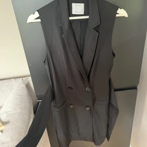 Svart klänning från Bershka - Snygg svart klänning från Bershka med dubbelknäppning och klassisk krage. Band som du antingen kan knäppa baktill eller framtill. Storlek S! Köparen står för frakt 💕