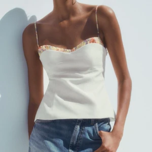 Vit blommig linnetopp med smala axelband - Säljer denna slutsålda superfin vit linnetopp med smala axelband och blommigt mönster längs kanten och banden. Den är från Zara i XS, prislappen är kvar!