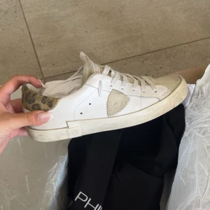 Philippe Model sneakers med leoparddetalj - Snygga vita låga sneakers från Philippe Model med beige mockadetaljer och leopardmönstrad häl. De är lite smutsiga men kan såklart tvätta innan jag postar dom, det är ingen skada eller något på skorna💓