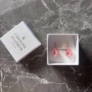 Rosa örhängen Caroline Svedbom - Superfina droppformade örhängen från Caroline Svedbom med rosa kristaller och guldfärgade detaljer. Kommer i originalask. Aldrig använda, bara testade🌸 Nypris: 695 kr