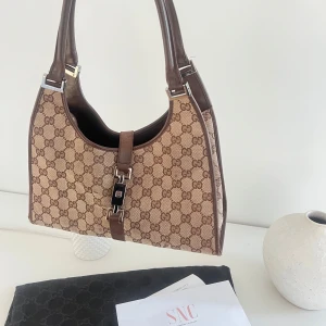 Gucci Jackie GG axelväska brun canvas - Säljer en Gucci Jackie axelväska i brun canvas med klassiskt GG-monogram. Köpt på SNC vintage & äktahetsbevis + dustbag medföljer självklart (foto på äktahetsbevis skickas närmre vid intresse) 🩷hör av er vid frågor eller fler foton!