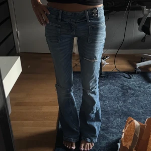 Blå bootcut jeans med slitningar - Snygga blå lågmidjade bootcut jeans med slitningar på knäna och framsidan. Bara använda några gånger alltså som nytt skick. Super populära och helt slutsålda🌸