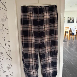 Rutiga pyjamasbyxor från M&S  - Snygga rutiga pyjamasbyxor från M&S i mjuk bomull. Byxorna har elastisk midja och ett klassiskt rutmönster i svart, grått och ljusrosa. Minsta midjemåttet: 38cm men mycket strecht i midjan. Innerbenslängd: 75cm. Läs gärna bio💕