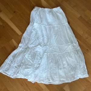 Vit långkjol från Gina Tricot - Luftig och flowy vit långkjol från Gina Tricot i storlek S. Kjolen har resår i midjan och flera volanger som ger en snygg boho-vibe. Perfekt för varma dagar och enkel att styla med crop tops eller linnen.