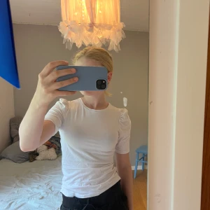 Vit topp med puffärm från ONLY XS - Säljer en vit topp från ONLY i storlek XS. T-shirten har korta puffärmar och rund halsringning. Materialet känns mjukt och stretchigt, perfekt för en clean och enkel look. Passformen är normal och toppen är lätt att matcha med allt.