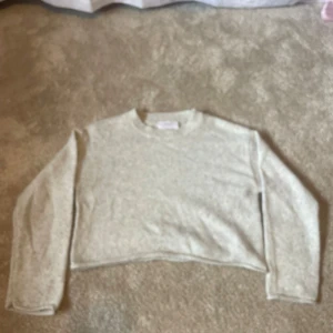 Ljusgrå croppad stickad tröja Zara - Supermysig ljusgrå croppad stickad tröja från Zara. Tröjan har rund halsringning, långa ärmar och en relaxed fit som ger en chill vibe. Perfekt att slänga på sig över ett linne eller t-shirt när det är lite kyligt ute.