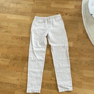 Vita linnebyxor från WAI WAI - Snygga och luftiga vita linnebyxor från WAI WAI med resår i midjan. Perfekta för varma dagar och har en rak passform som ger en chill vibe. Byxorna är tillverkade i linne och har en enkel, stilren look utan mönster eller extra detaljer.