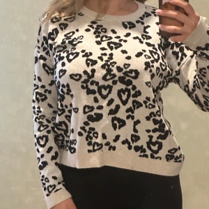 Beige leopardmönstrad tröja - Snygg beige tröja med svart leopardmönster och hjärtformade detaljer. Tröjan har rund halsringning och långa ärmar, perfekt för dig som vill sticka ut lite extra. Mjuk och skön att bära till både jeans och kjol.