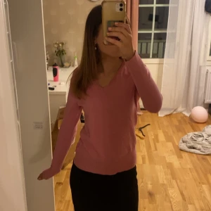 Rosa v-ringad tröja från bpc - Snygg rosa tröja från bpc med v-ringning och långa ärmar. Tröjan är i mjuk bomullsmix och har ribbade muddar vid ärmslut och nederkant. Perfekt till jeans eller kjol för en chill och stilren look.